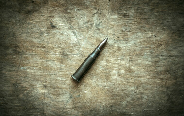 An old metal cartridge with a bullet from a Mosin rifle on a wooden table in a retro style