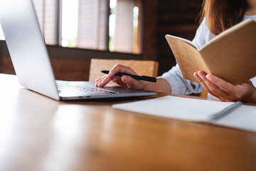 Closeup image of a woman working on paperwork and laptop computer in office