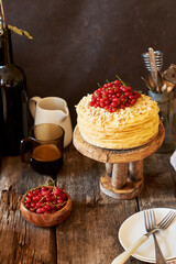 Cake on a wooden cake stand. Shortcrust pastry cake, decorated with red currants. Wooden background, side view.
