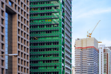 Fototapeta premium Focus on foreground at row of high residential buildings with blue sky in perspective side view that one building is under construction 