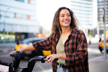 Young lady on electric bicycle on the street. Beautiful girl riding a bicycle in the city.