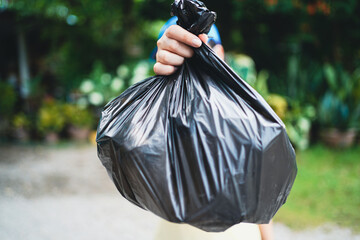 Volunteer charity woman hand holding garbage black bag and plastic bottle garbage for recycling for cleaning at park volunteering concept reuse and volunteer helping