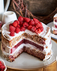 Vegan cake with raspberries, raspberry confit, coconut cream and almond biscuit. No flour. Side view, wooden background