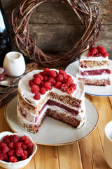 Vegan cake with raspberries, raspberry confit, coconut cream and almond biscuit. No flour. Side view, wooden background