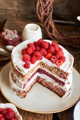 Vegan cake with raspberries, raspberry confit, coconut cream and almond biscuit. No flour. Side view, wooden background