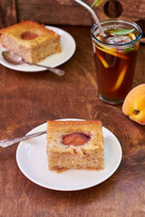 Vegetarian peach pie. The cake contains banana, coconut oil, sugar, flour and peaches. Wooden background.