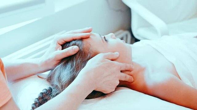 real doctor osteopath hands does physiological and emotional therapy for eight year old kid girl. pediatric osteopathy treatment session. alternative medicine. taking care of the child's health