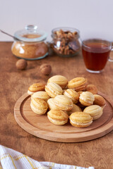 Walnut cookies with cream filling. Cookies on a wooden board. Side view, white and wood background. Tea.