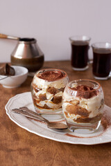 Tiramisu in a glass. Coffee, wooden and white background, side view