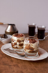 Tiramisu in a glass. Coffee, wooden and white background, side view