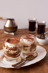 Tiramisu in a glass. Coffee, wooden and white background, side view