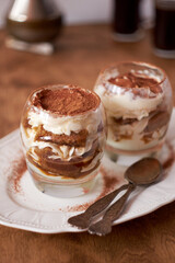 Tiramisu in a glass. Coffee, wooden and white background, side view