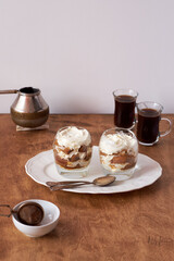 Tiramisu in a glass. Coffee, wooden and white background, side view