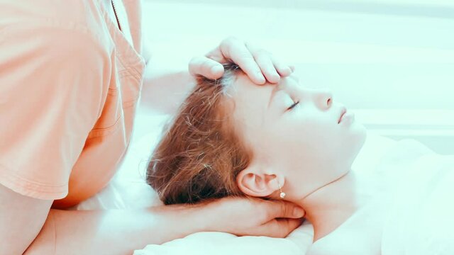 real doctor osteopath hands does physiological and emotional therapy for eight year old kid girl. pediatric osteopathy treatment session. alternative medicine. taking care of the child's health