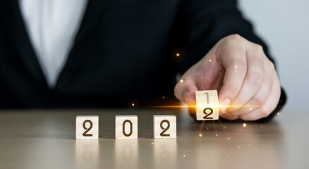 man's hand flipping a wooden block with 2022 message on the wooden cube. Space for text and designs, copy space. new year concept and setting goals in the starting