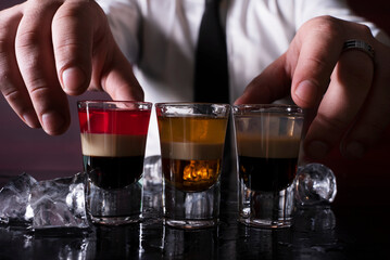 Barman preparing cocktail shots at the bar counter. Barman mixing drinks at the night club