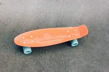 penny board on the asphalt. small plastic skateboard. pink penny Board with blue wheels