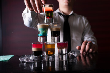 Barman preparing cocktail shots at the bar counter. Barman mixing drinks at the night club