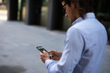 Close up of businessman using the phone. Young manager typing a message.