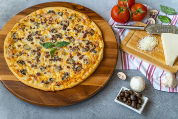 Hot pizza with ham, bechamel sauce, mushrooms, bacon, cheese, olives and basil. 