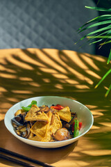 Fried tofu in sweet and sour sauce with Sichuan pepper and vegetables in a white plate. Chinese cuisine