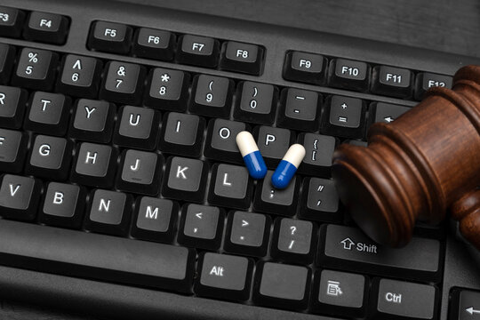 Pills and judge gavel on keyboard. Online sale of drugs is illegal. Darknet drug trade concept