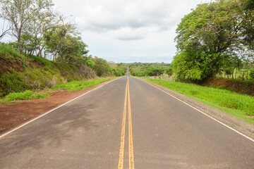 straight asphalt road that disappears into the horizon surrounded by trees in Panama, Central America