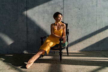 attractive woman in yellow summer dress in interior room concrete wall background