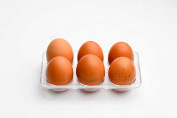 Organic eggs in transparent package, on white background. Raw chicken eggs, from the home market. Used in the kitchen and in the bakery: essential ingredient to make sauces and desserts.