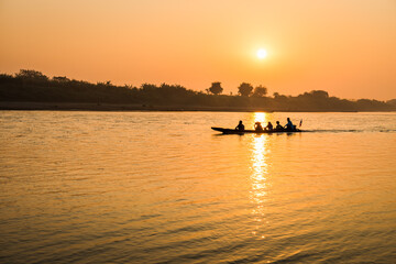Fishermen in the boat on sunrise background