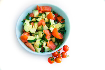 Vegetable salad in a plate on a white background. Chopped onions, tomatoes, cucumbers. Healthy food.