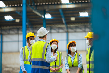 The factory employee consists of engineers, foreman, technicians, and related department staff. Wear a mask, hard hat, and vest. meeting before starting work inside the warehouse. Teamwork concept.