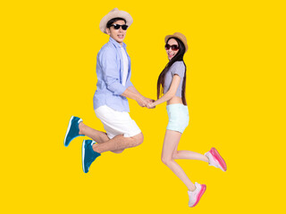 Fototapeta na wymiar Young couple in sunglasses and jumping together .Isolated on yellow background.