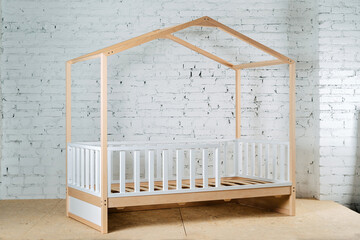 Children's wooden bed in the form of a house on a background of a brick wall.