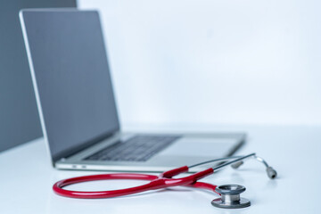 Stethoscope and computer on white desk in white background