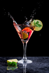 A splash of a pink margarita cocktail in a cocktail glass and a slice of lime
