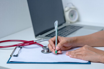 the doctor is analyzing the illness A stethoscope and computer are placed on a white desk in a white background.