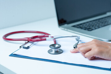 the doctor is analyzing the illness A stethoscope and computer are placed on a white desk in a white background.
