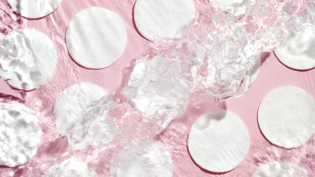 Multiple waves of water cross each other creating ripples and bubbles spontaneously on cotton pad background | Make-up background shot for its commercial