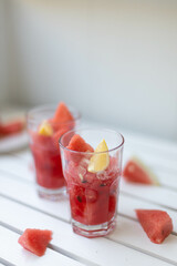 Fresh summer watermelon drink in a glass glass and a piece of watermelon on a wooden board. Vertical photo orientation