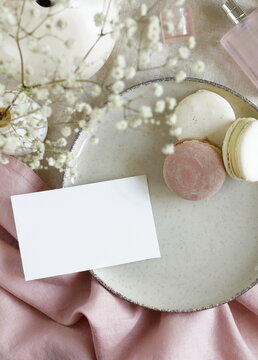 Sheet card mockup , wedding invitation, macaroons, perfume, white flowers on beige linen background. Copy space. Scandinavian life  style.
