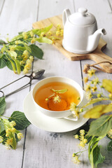 Lime leaf tea. Cup of herbal linden tea with linden flowers and teapot