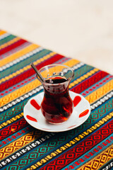 close-up of turkish tea in a transparent glass on a table with a colorful tablecloth