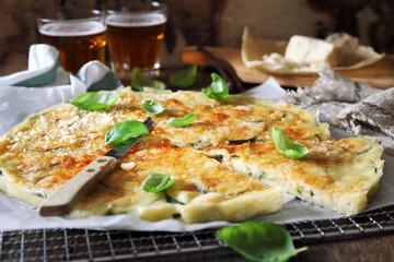 Italian cuisine. Thin zucchini pie with Parmesan cheese, basil dressing and two glasses of beer