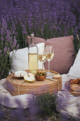 Beautiful picnic with wine, cheese, olives, ciabatta bread and croissants in a lavender field.