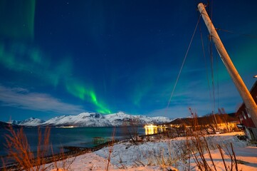 Northern lights over the snow capped mountains in the night in the arctic area of Norway