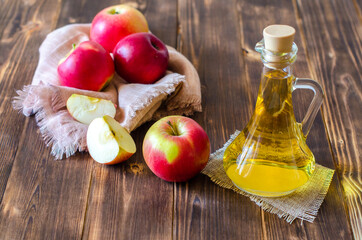 Apple cider vinegar in a glass bottle on a wooden table. Malic acid, the result of fermented apple...