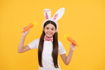Obraz na płótnie Canvas happy easter teen girl in bunny ears and bow tie hold carrot, easter