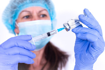 female doctor in protective mask and gloves is typing vaccine into syringe. Close-up. virologist...