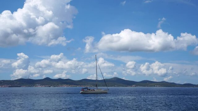 ZADAR, CROATIA - Jul 05, 2021: A sailboat swimming on the water with mountains in the distance in Zadar, Croatia